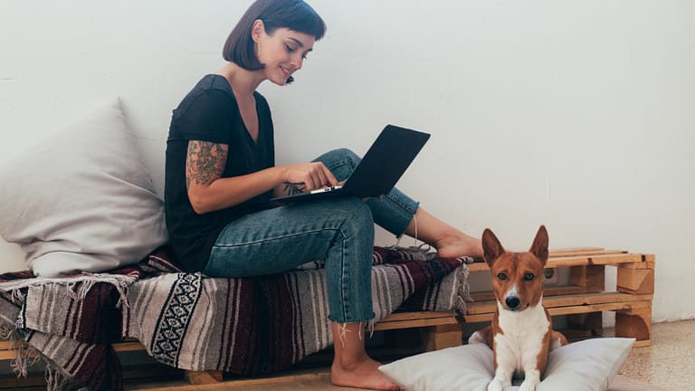 a woman using a laptop while sitting on a bench